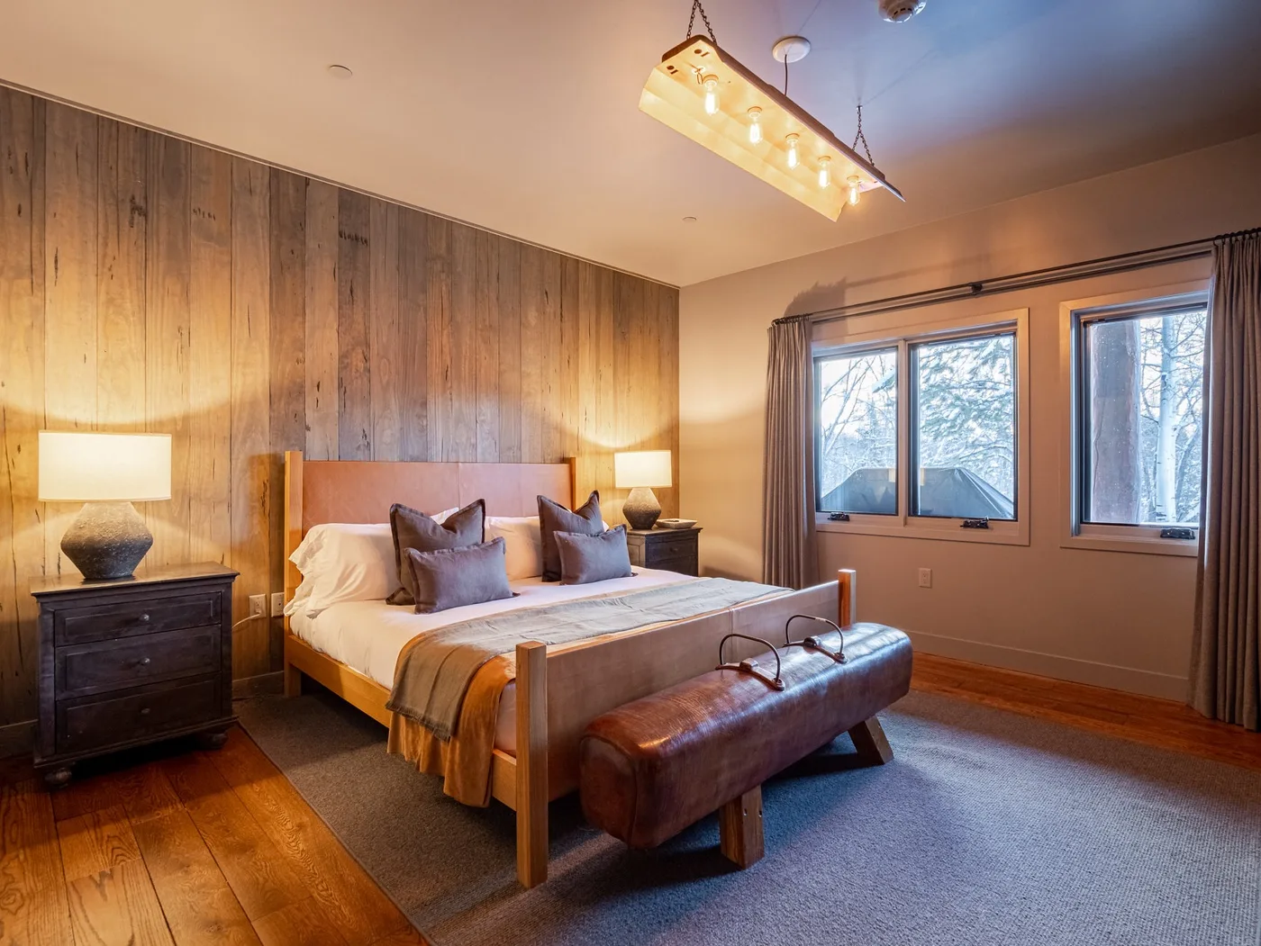 A bedroom with a wooden bed, bedside tables, and a bench at the foot.