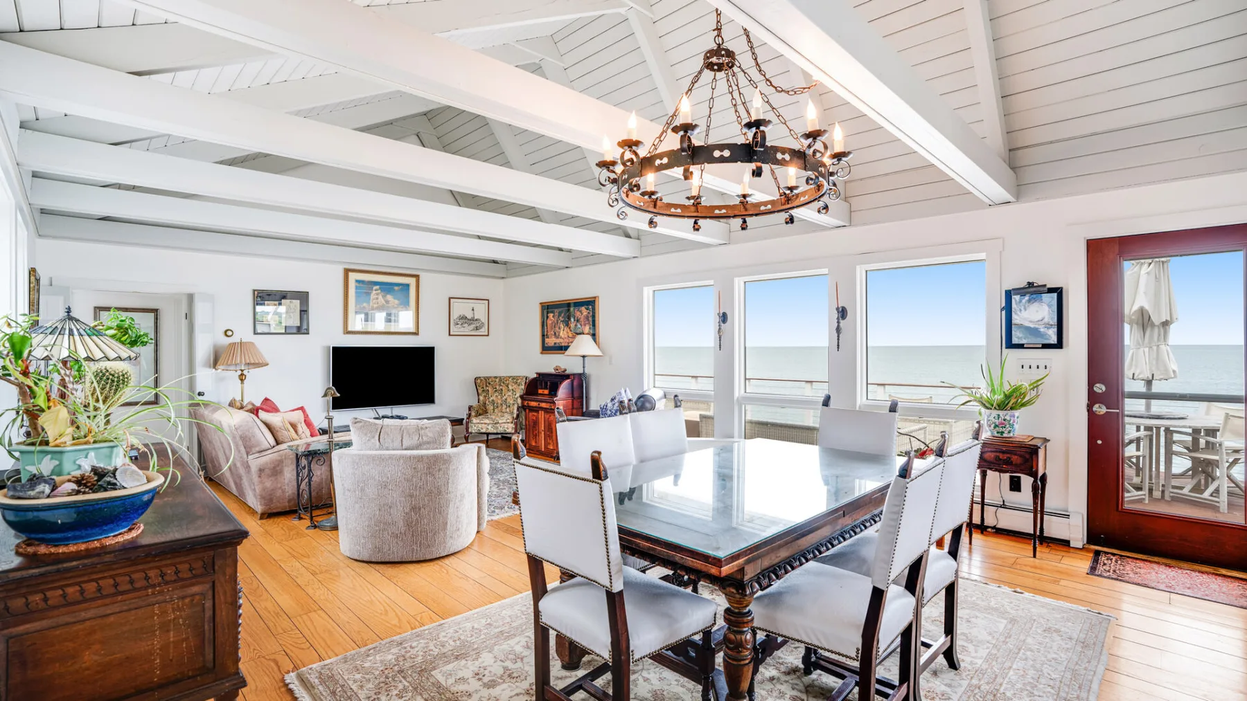 Un luminoso salón-comedor de planta abierta con una mesa grande y vistas al mar.