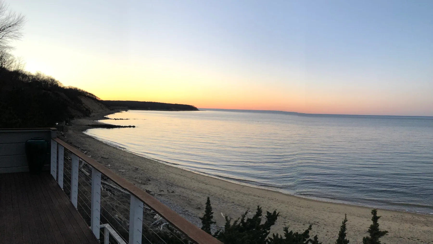 Una playa de arena y aguas tranquilas se extienden por la costa al atardecer.