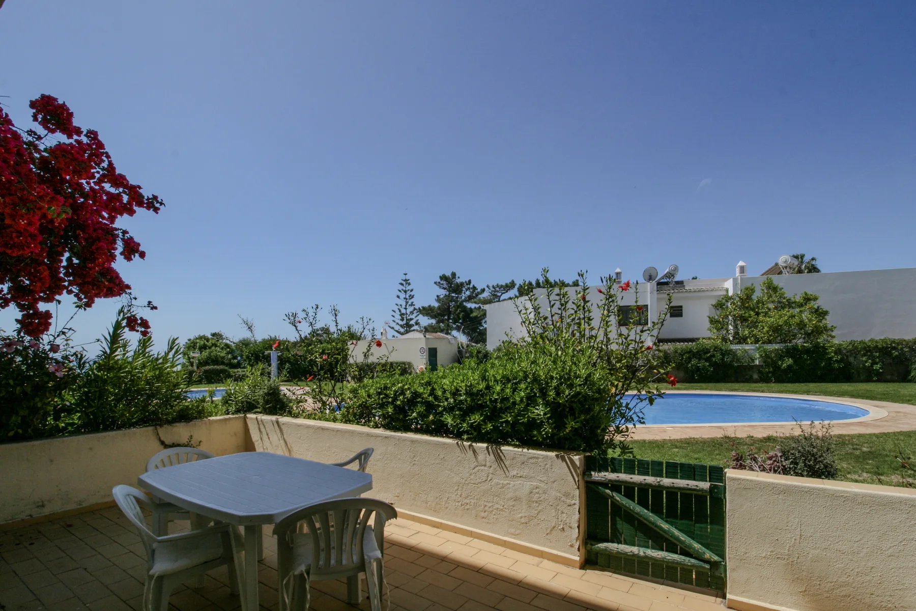 Un patio exterior con una mesa y asientos da a una piscina.