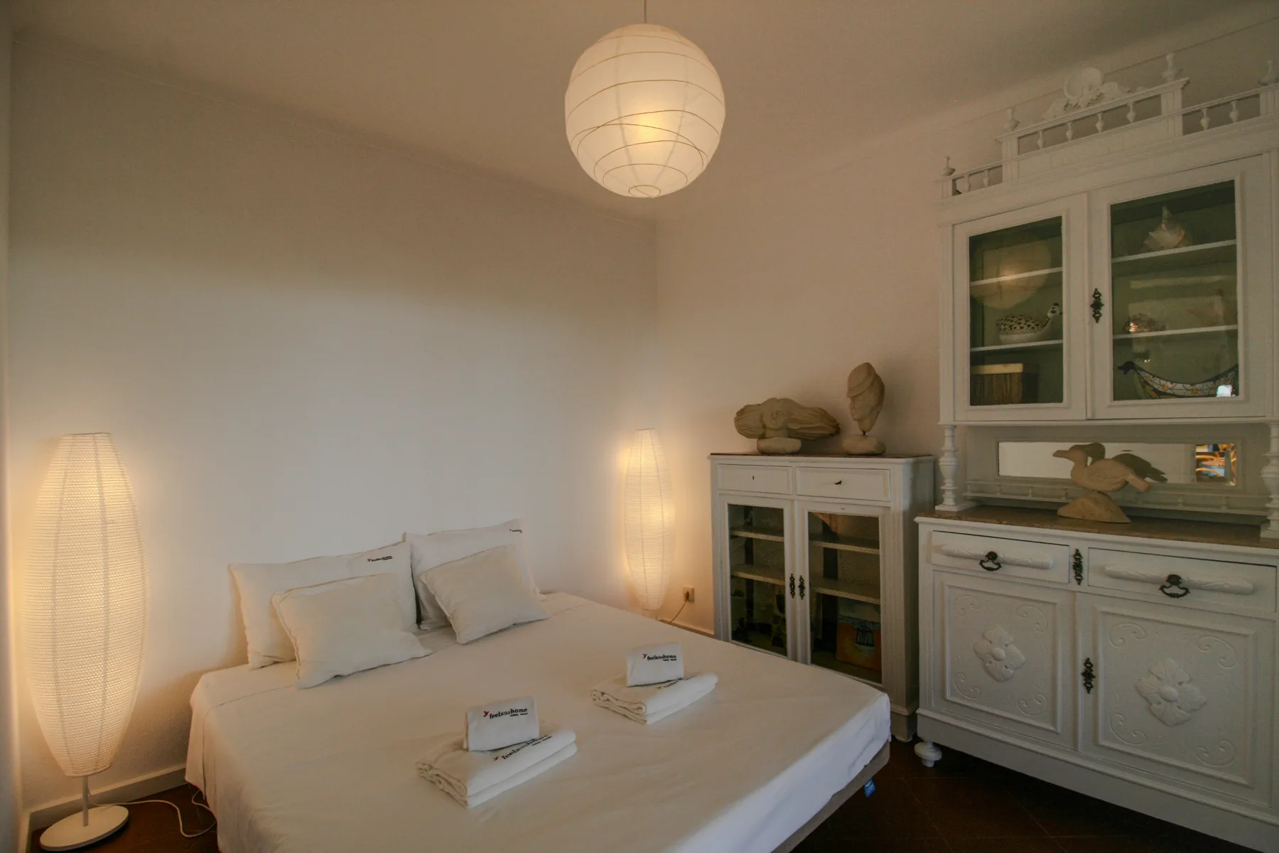Un dormitorio con una cama y un armario blanco junto a la pared.