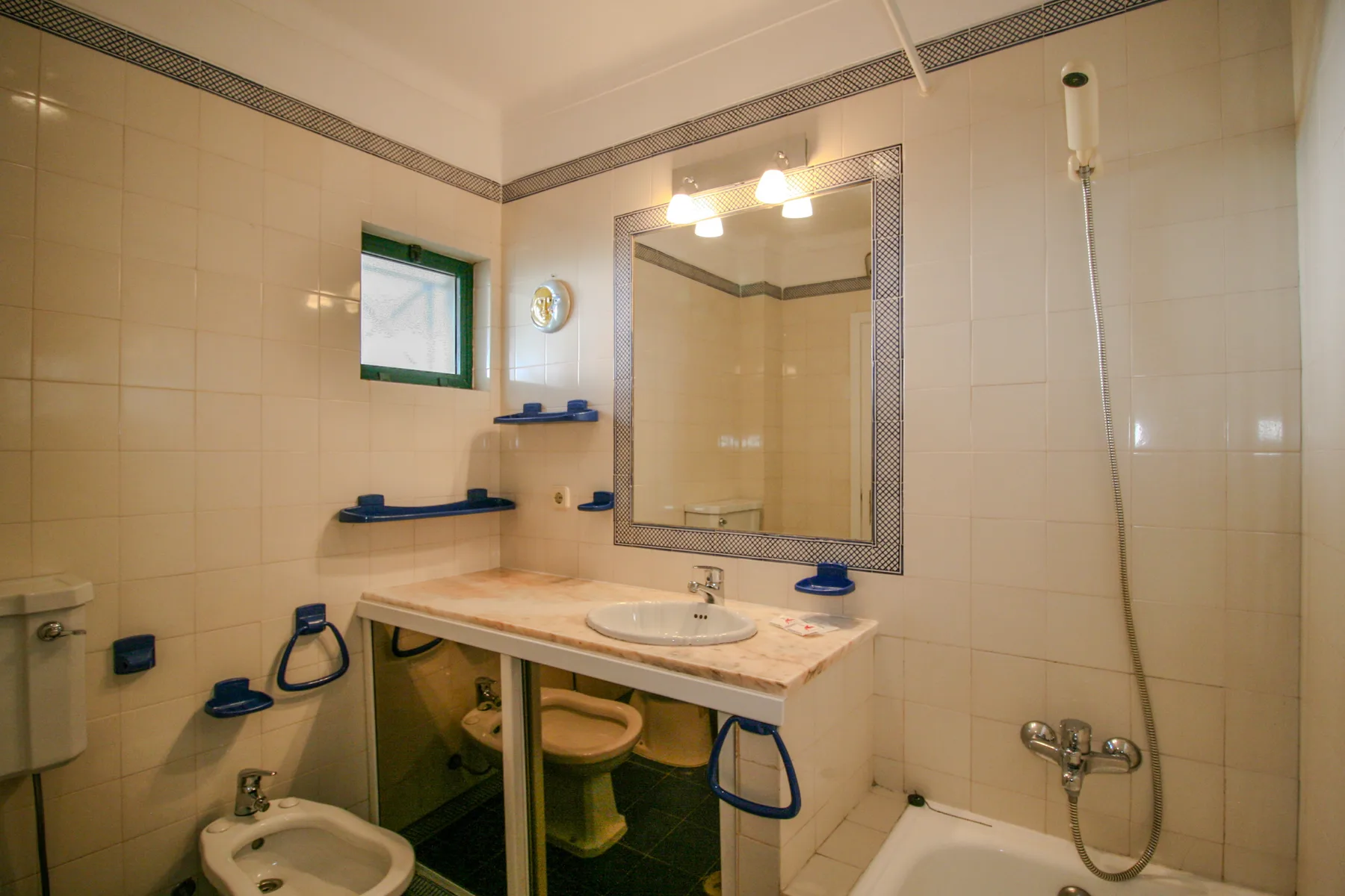 A tiled bathroom with a sink, mirror, and shower.
