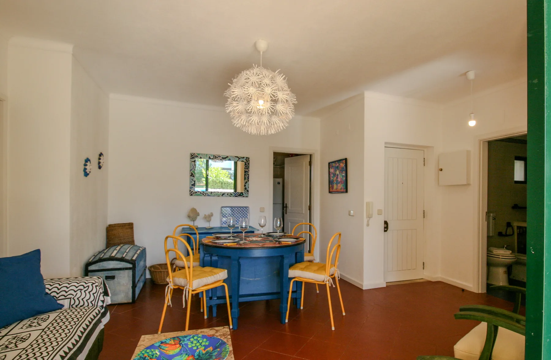 Comedor con una mesa azul y sillas amarillas junto a la zona de estar.
