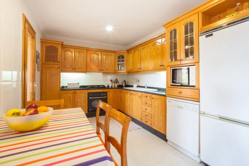 Una cocina con gabinetes de madera, encimeras oscuras y una mesa a rayas.