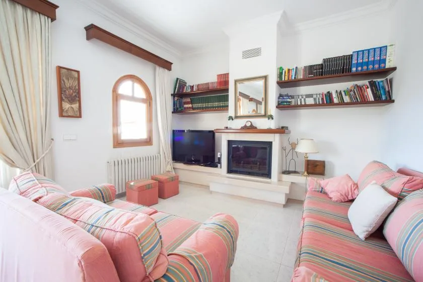 Una sala de estar con asientos rosas, una chimenea y estanterías.