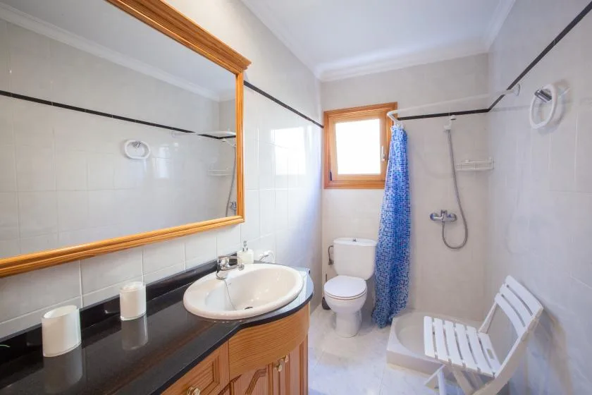 Un baño con azulejos, lavabo, inodoro y cortina de ducha azul.