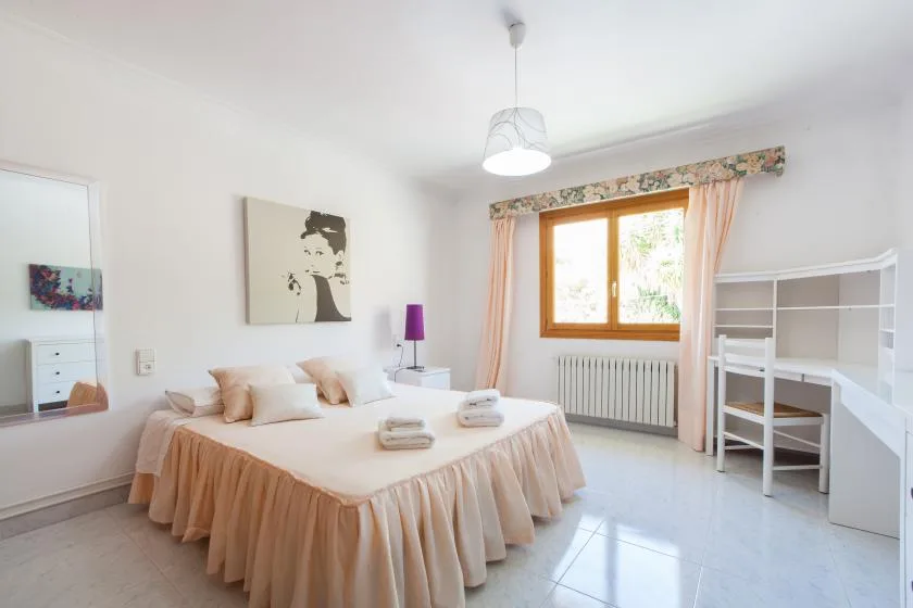 Un dormitorio luminoso con una cama doble, una ventana y estanterías blancas.