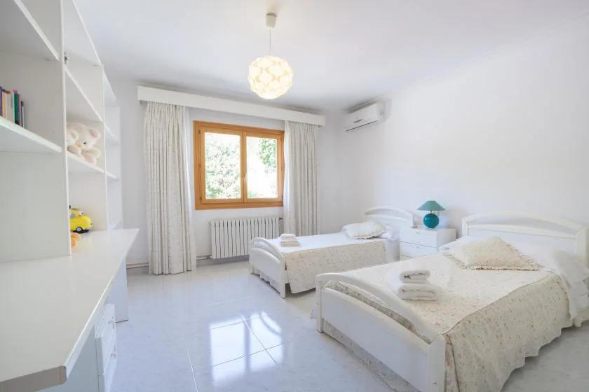 Un dormitorio luminoso con dos camas y una ventana enmarcada por cortinas.