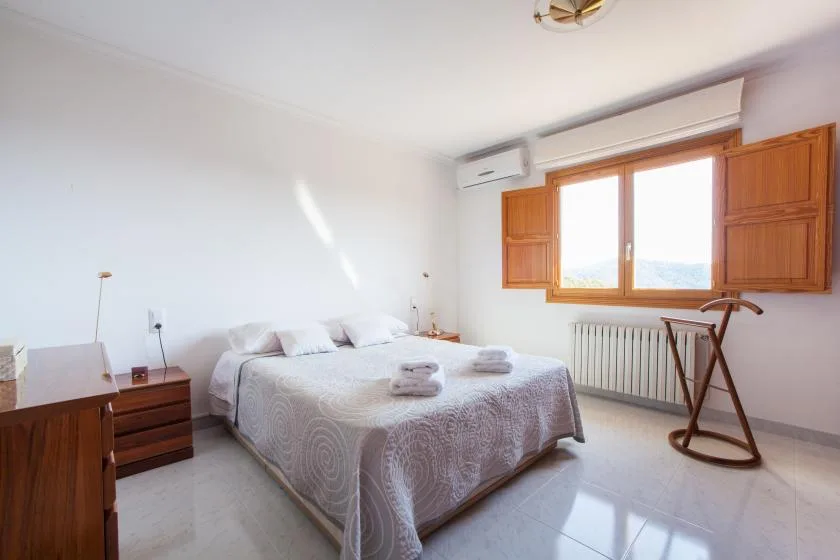 Un dormitorio con una cama doble bajo una ventana con contraventanas de madera.