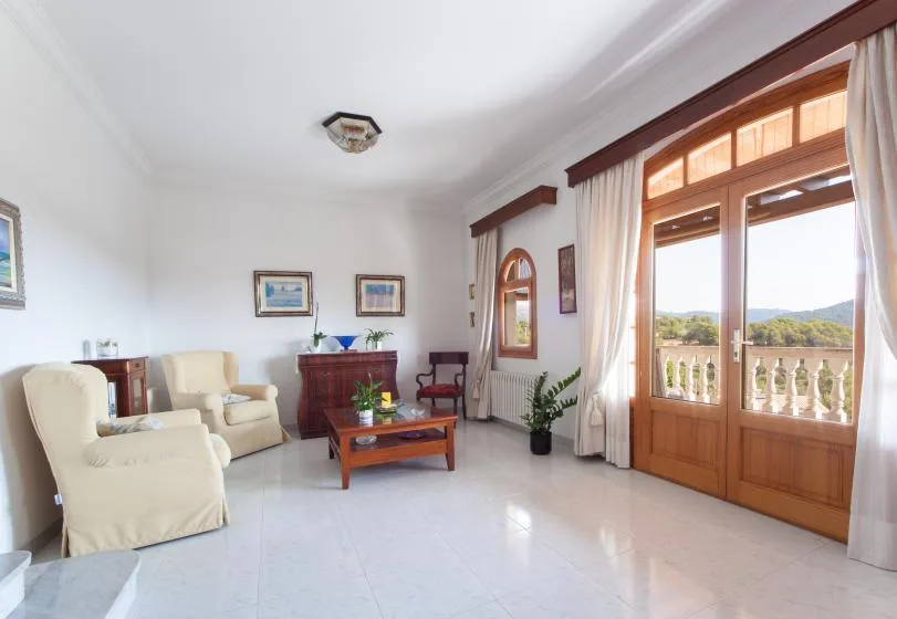 Una sala de estar luminosa con asientos, una mesa de centro y puertas de vidrio hacia un balcón.