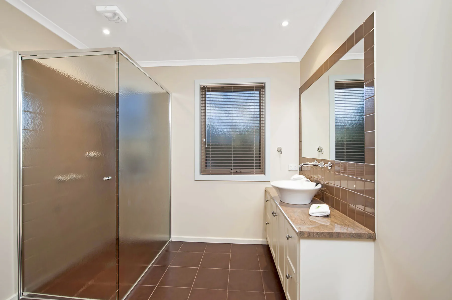 A bathroom with a glass shower and a sink beneath a mirror.