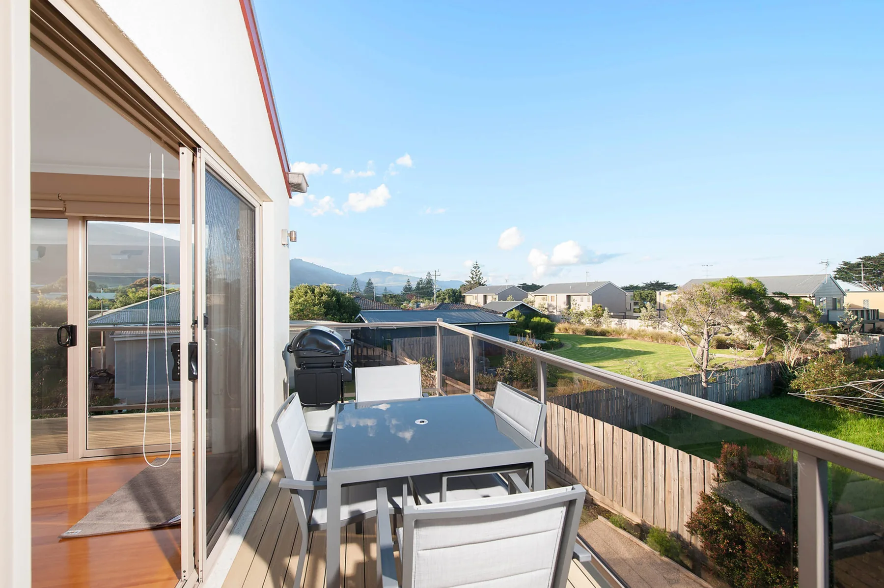 A balcony dining area overlooks neighboring homes and distant hills.