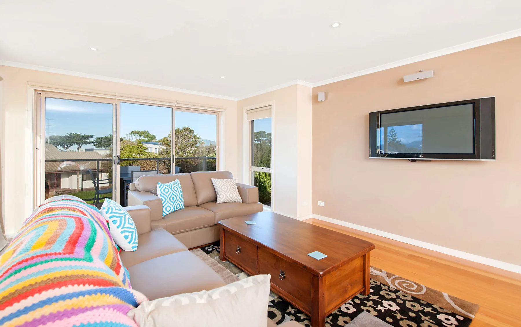 A bright living room with seating, a wooden coffee table, and large windows.