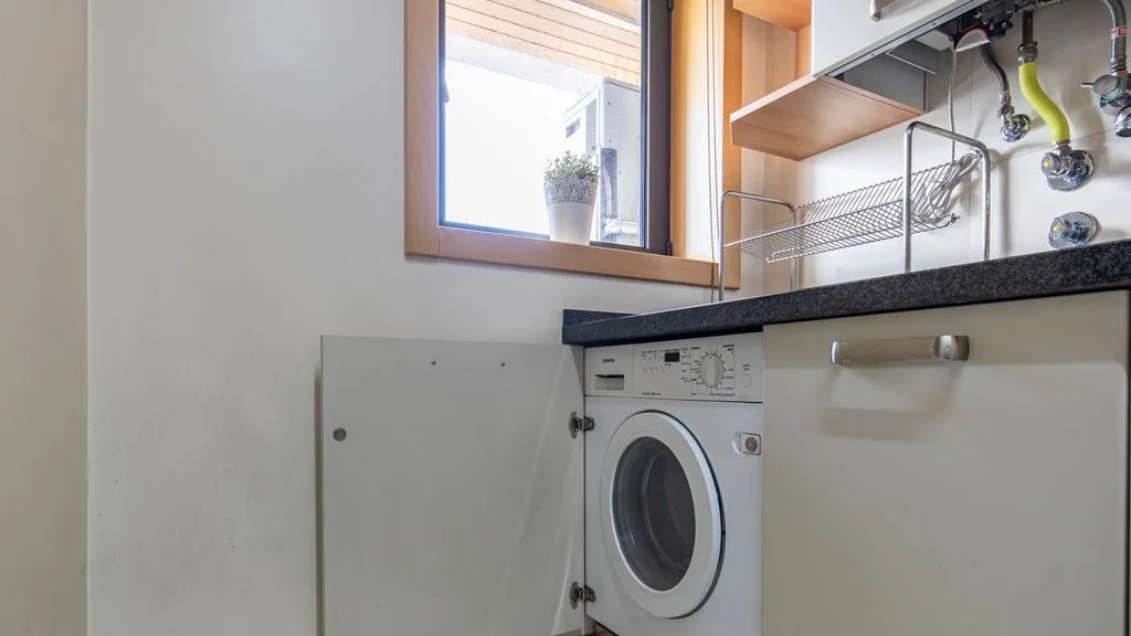 A laundry area with a front-loading washing machine beneath a countertop.