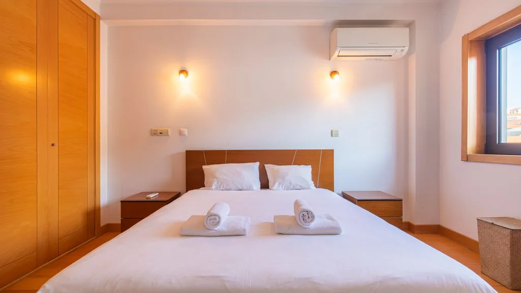A bedroom with a double bed, bedside tables, and a window.
