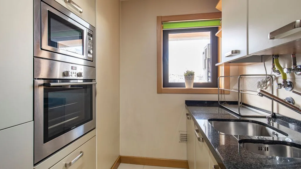 A kitchen with built-in appliances, a sink, and a window.