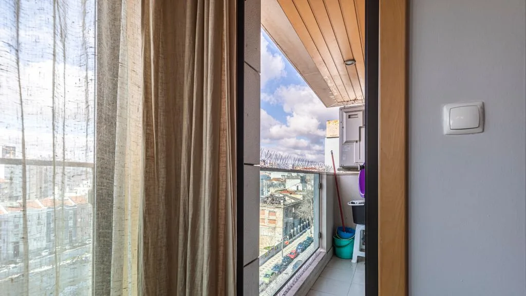 A glass balcony with a view of nearby buildings and the sky.