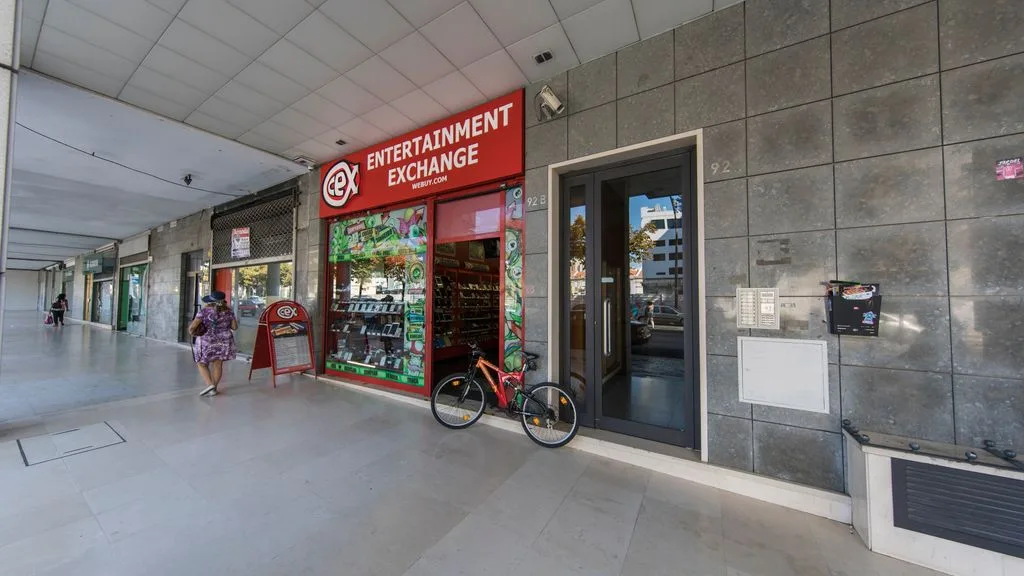 A covered sidewalk with a storefront and a bicycle parked beside the entrance.