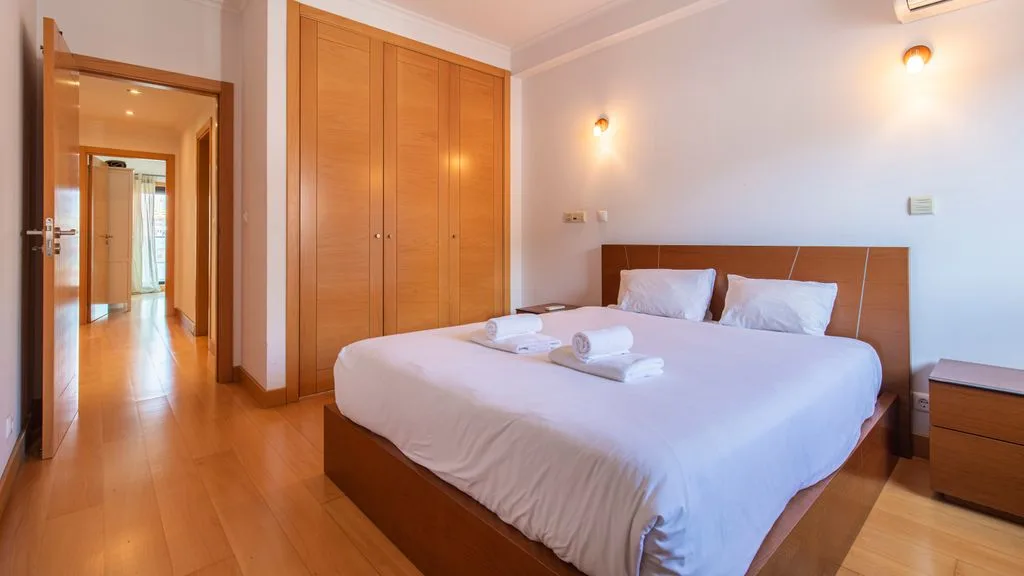 A bedroom with a neatly made bed and wooden wardrobes.