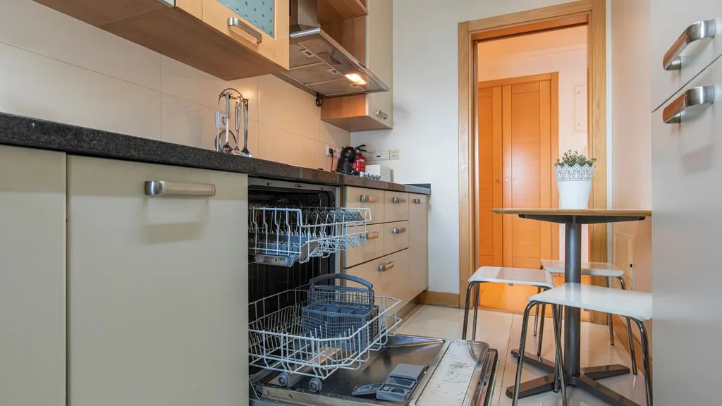 A compact kitchen with light cabinets, a dishwasher, and a small dining table.