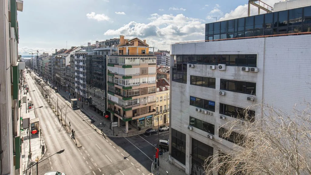 An urban street scene with rows of buildings and a wide road.