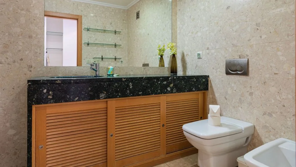 A tiled bathroom with a sink vanity and a toilet.