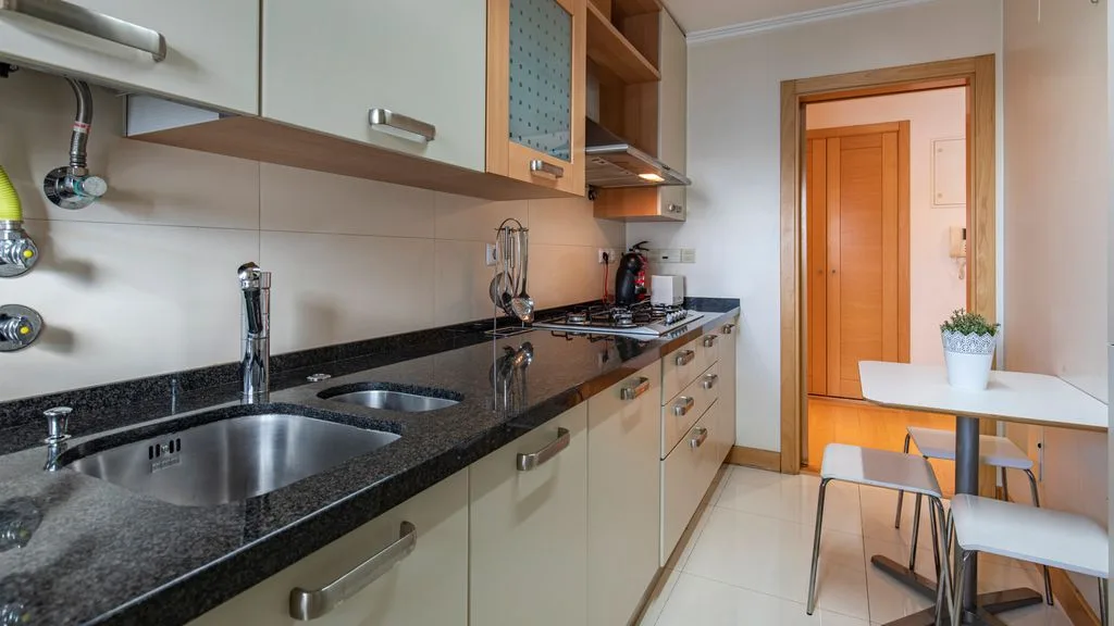 A compact kitchen with a dark countertop and a small dining table.