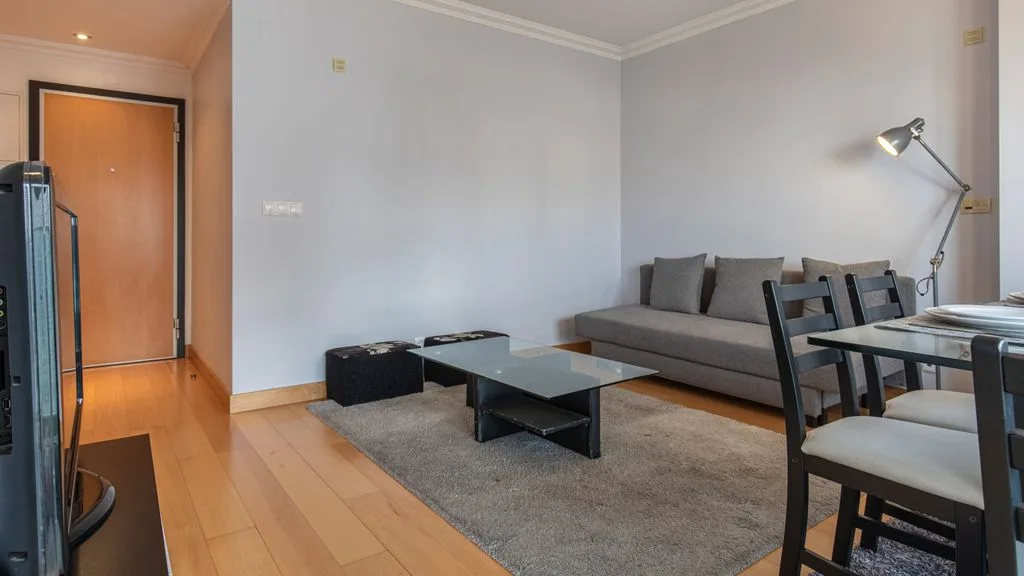 A living room with a gray sofa, coffee table, and dining area.