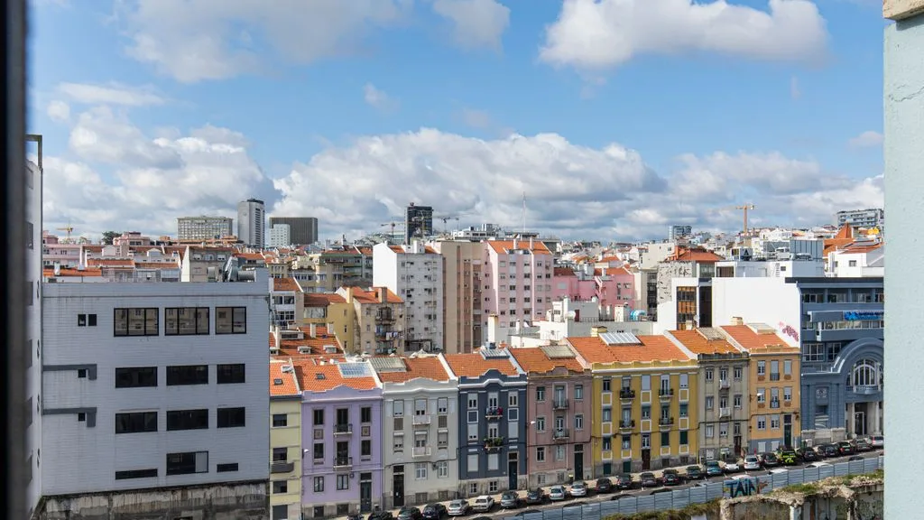 Cityscape of colorful urban buildings beneath a partly cloudy sky.