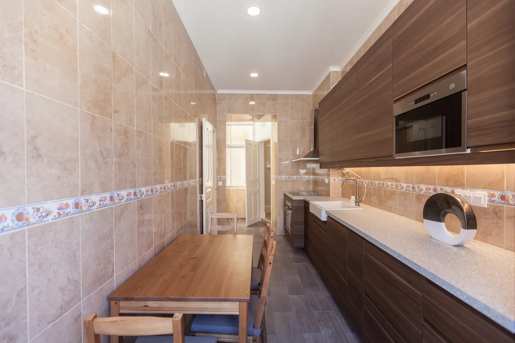 Una cocina estrecha con armarios oscuros y una mesa de madera.