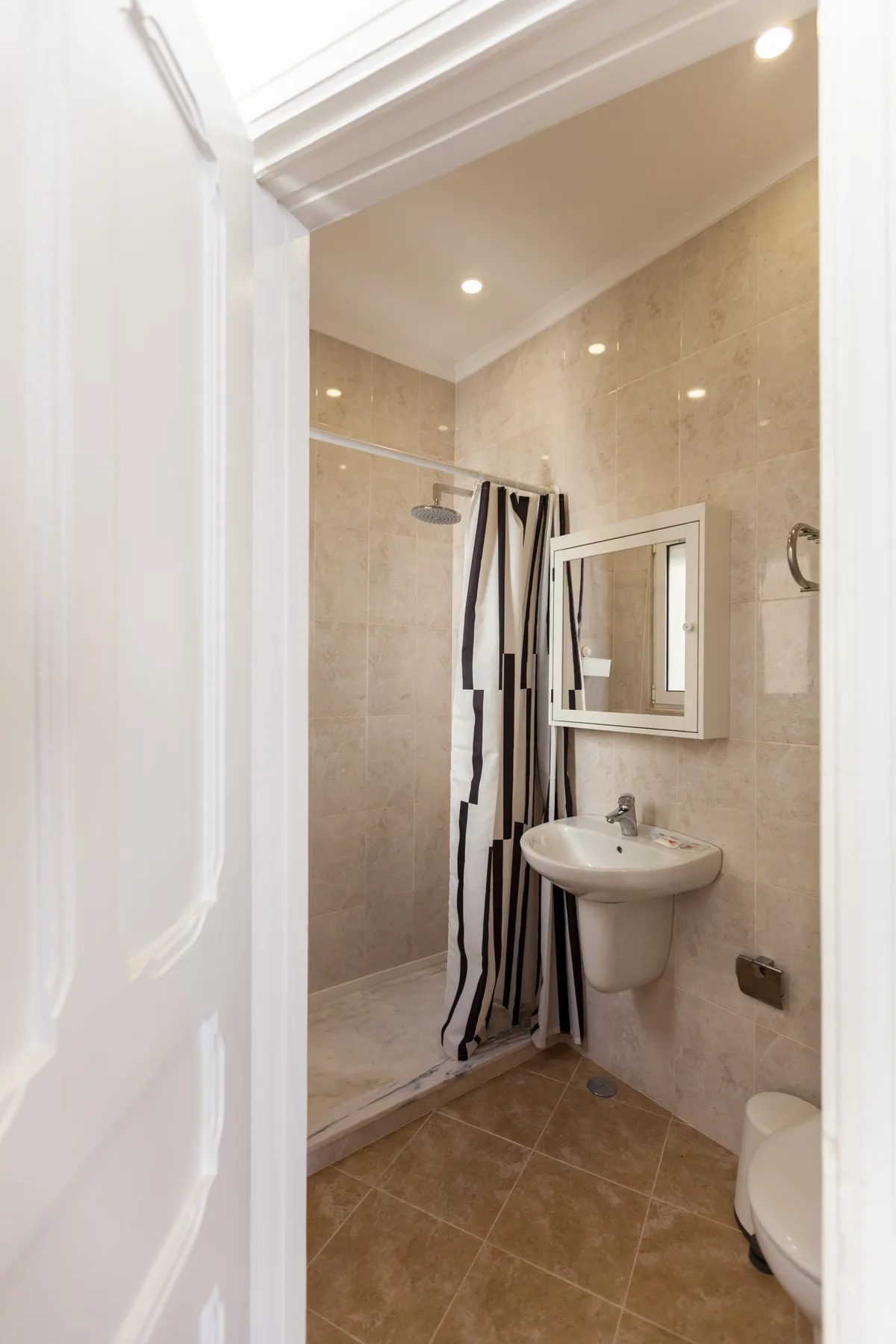 Un baño con lavabo, espejo y ducha con cortina.