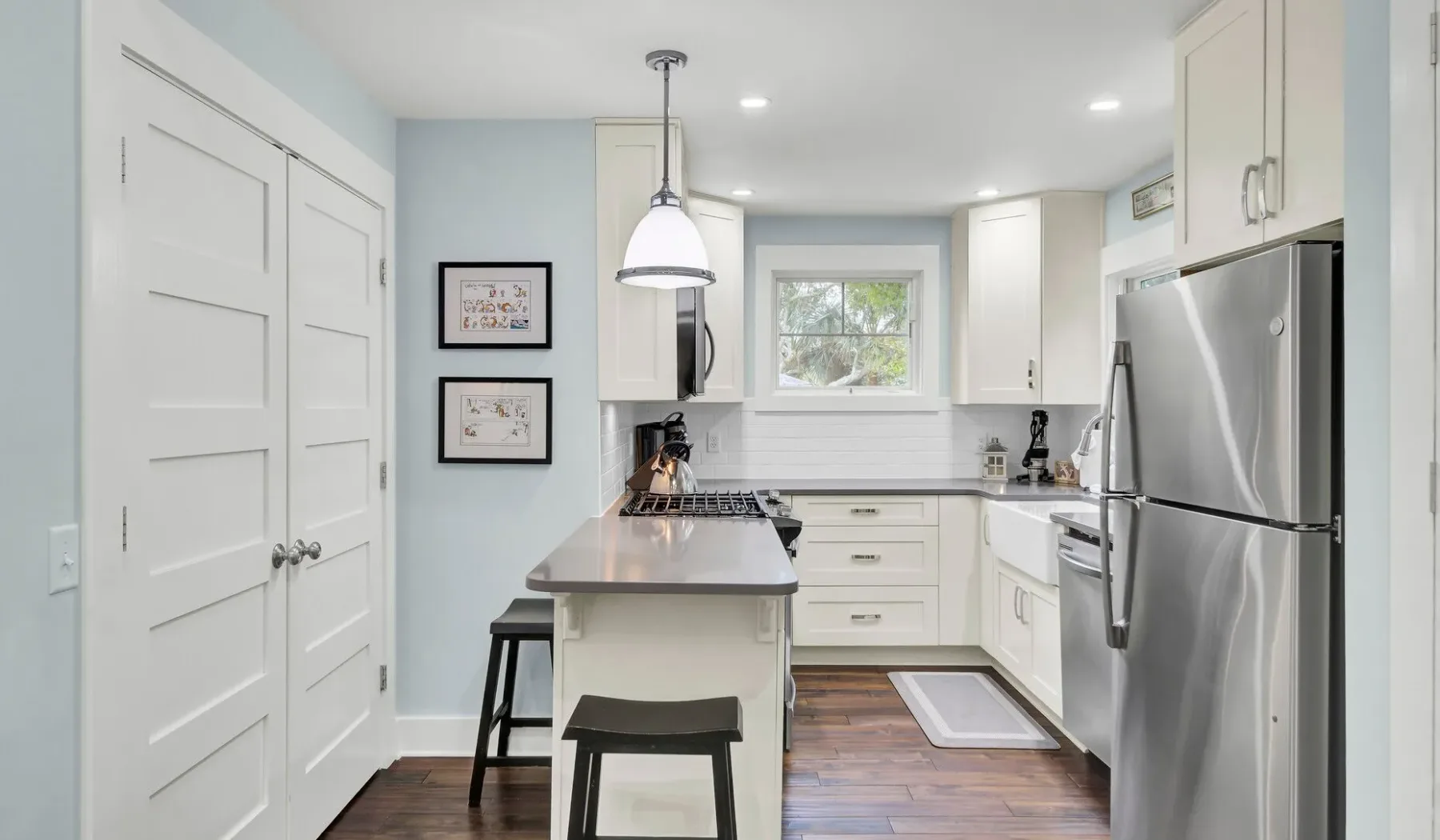 A bright kitchen with white cabinets, a central island, and stainless steel appliances.