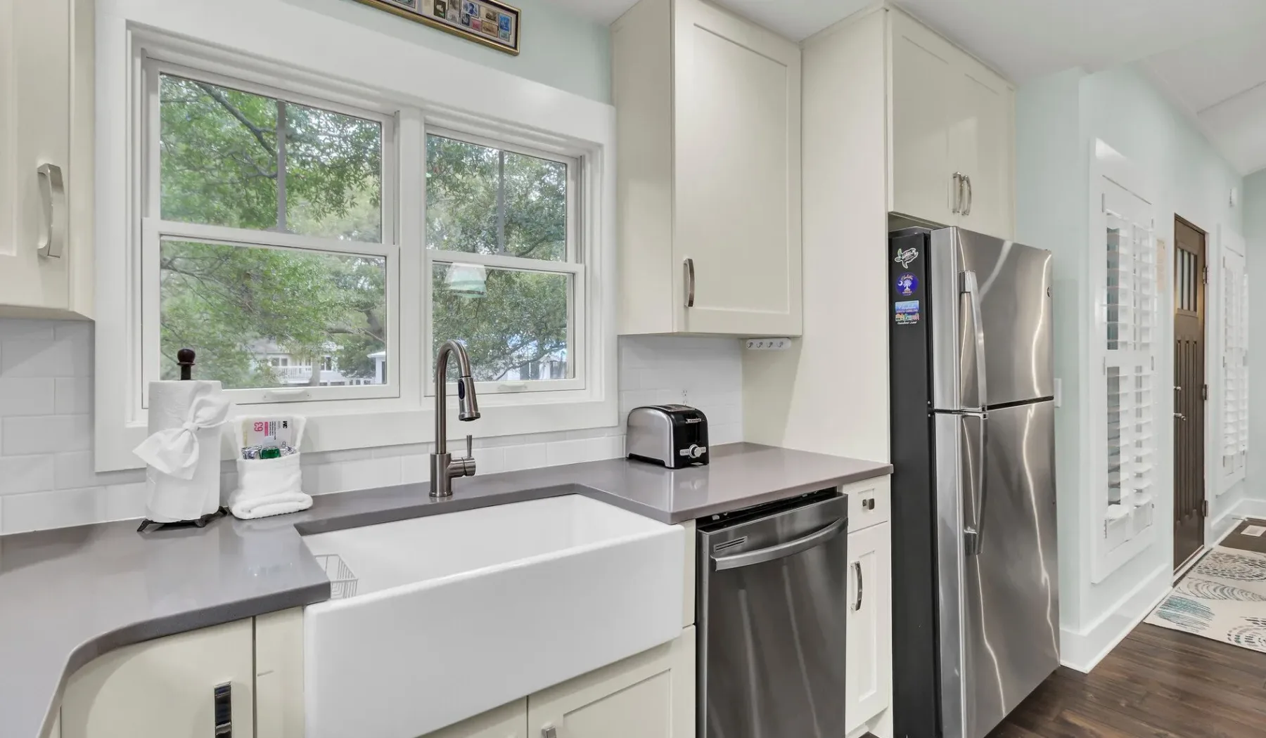 A bright kitchen with white cabinets, a large sink, and stainless steel appliances.