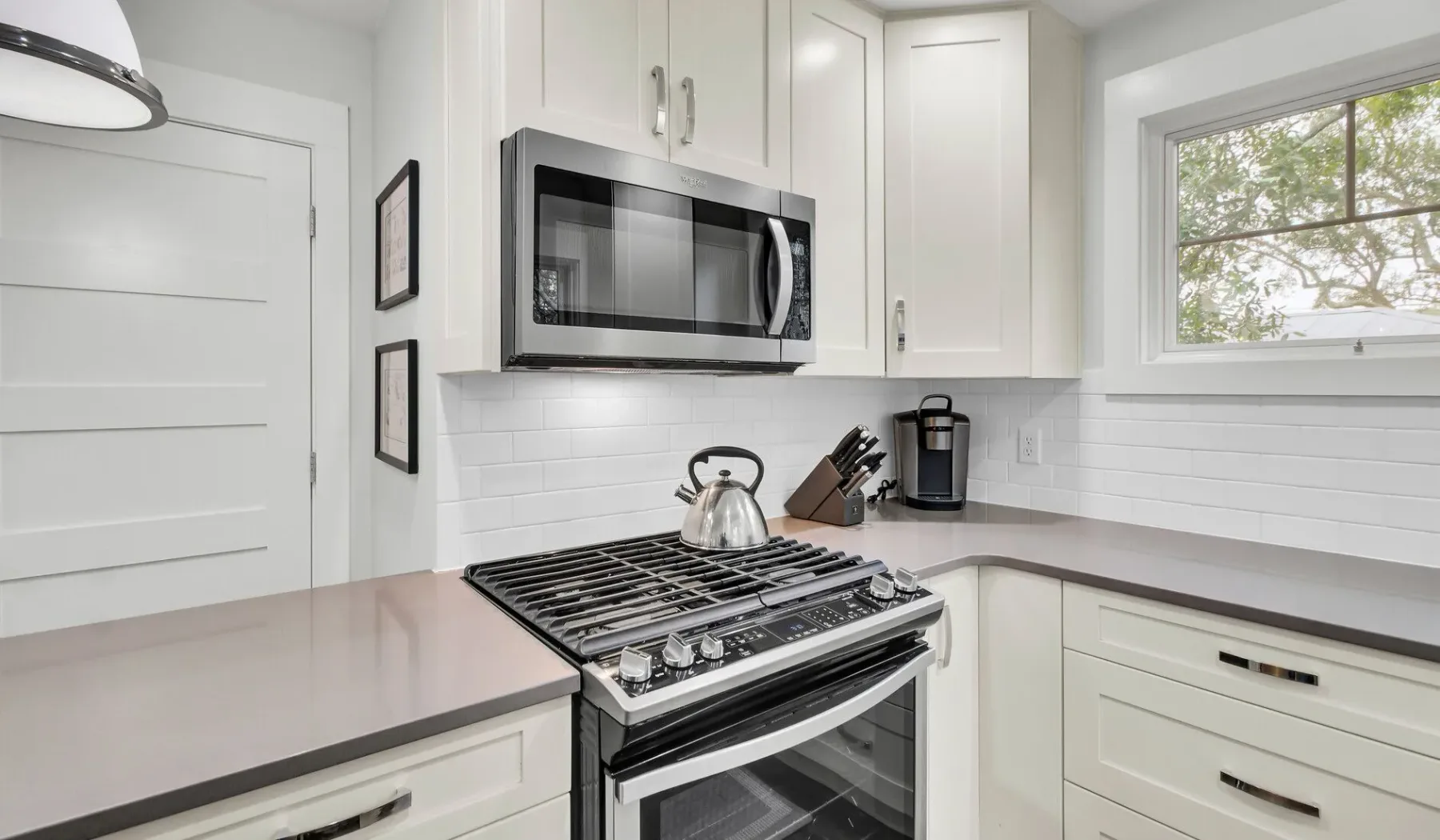 A bright kitchen with a gas range beneath a microwave.