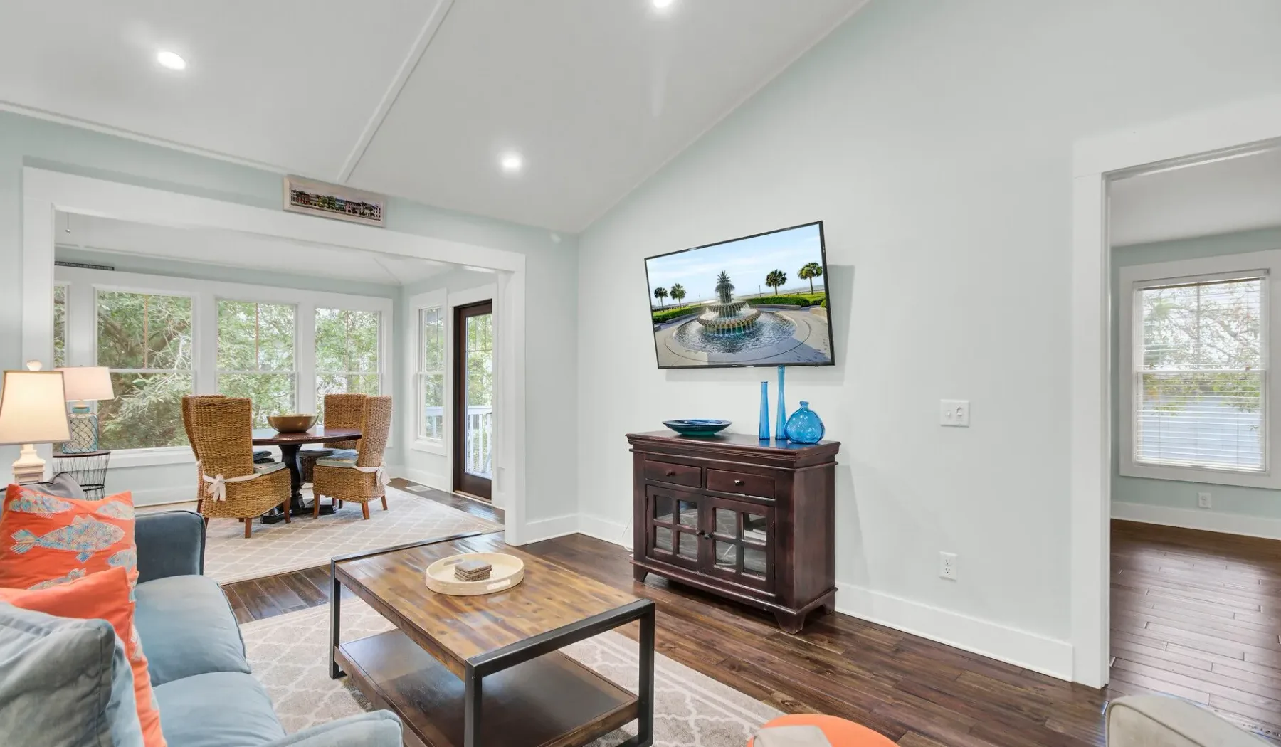 A bright living room with seating, a coffee table, and a dining area by the windows.