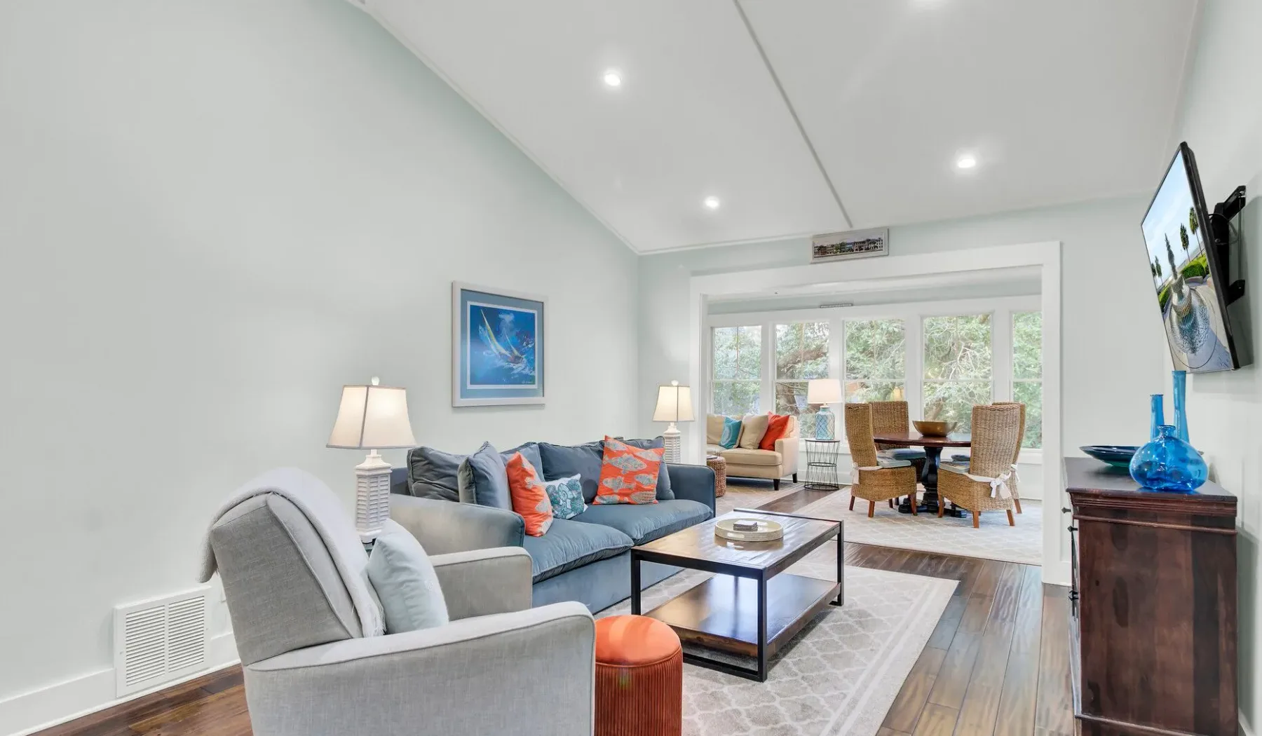 A bright living room with seating, a coffee table, and large windows.
