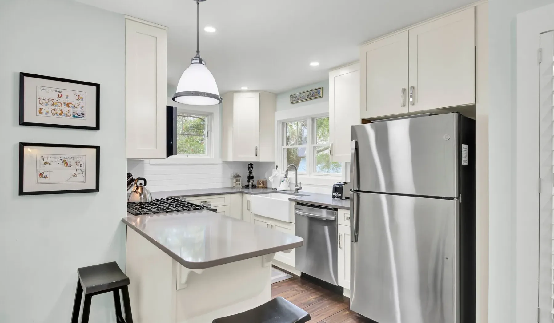 Una cocina luminosa con gabinetes blancos, electrodomésticos de acero inoxidable e isla central.