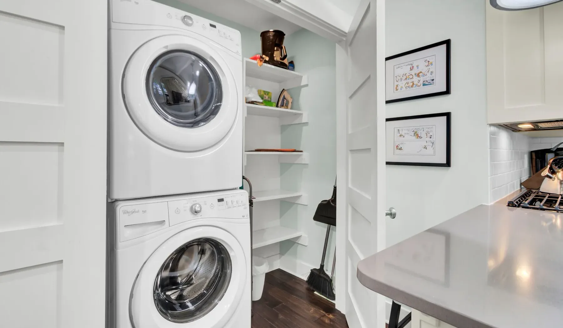 A laundry area with a stacked washer and dryer beside open shelves.