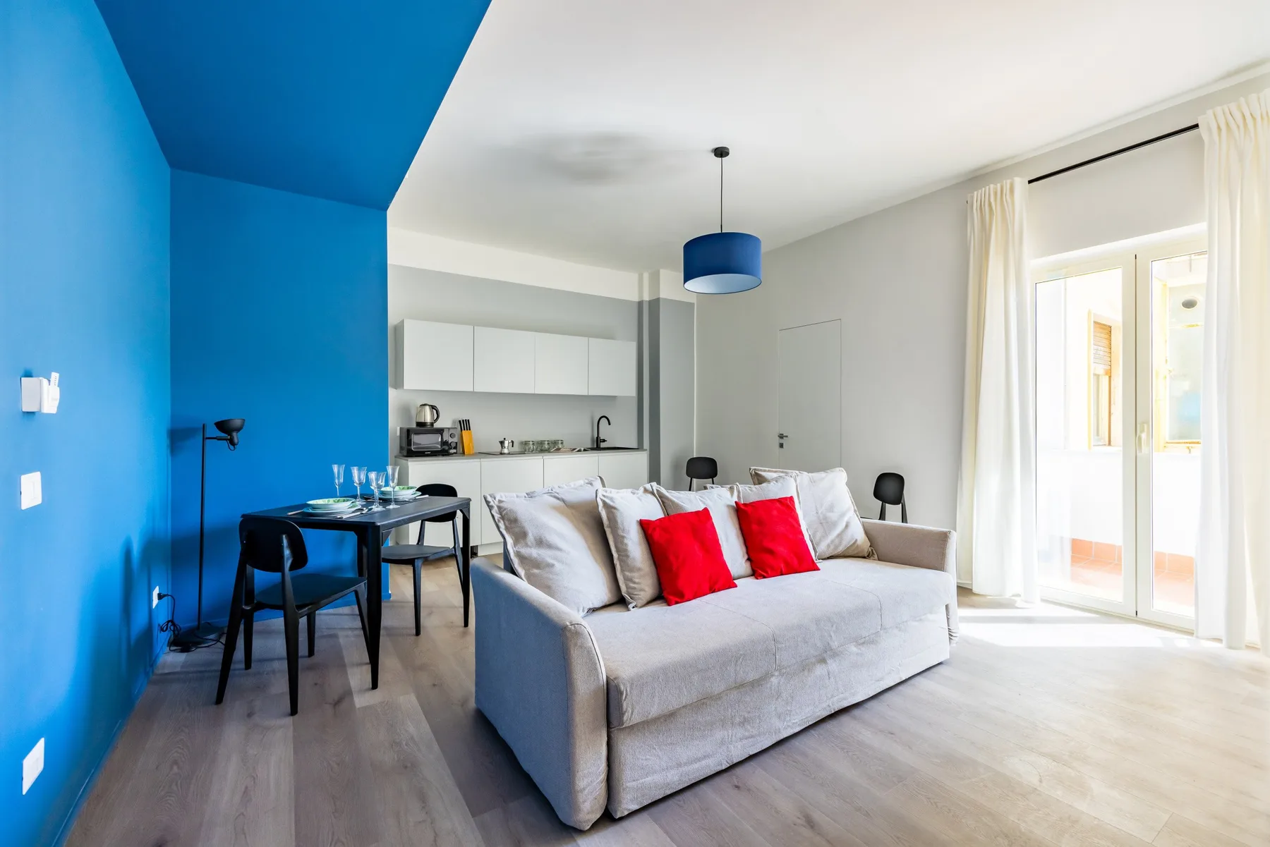 Una luminosa sala de estar con sofá, mesa de comedor y cocina abierta.