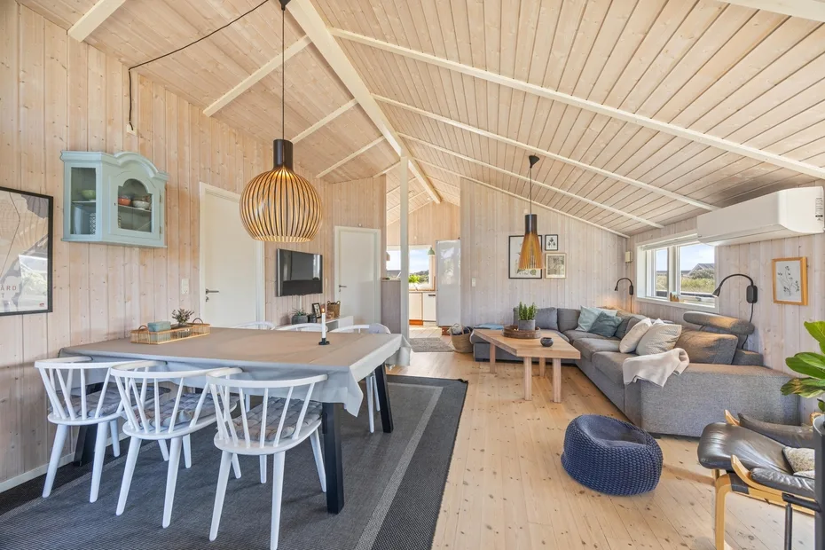 Un luminoso salón-comedor diáfano con una mesa y una zona de estar.