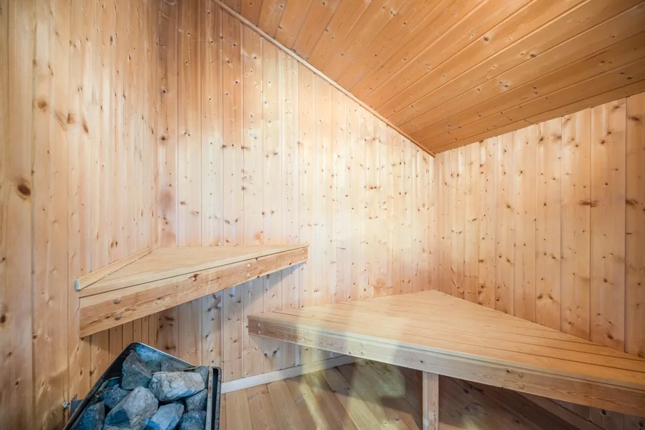 Una sauna revestida de madera con bancos escalonados y un calentador de piedras.