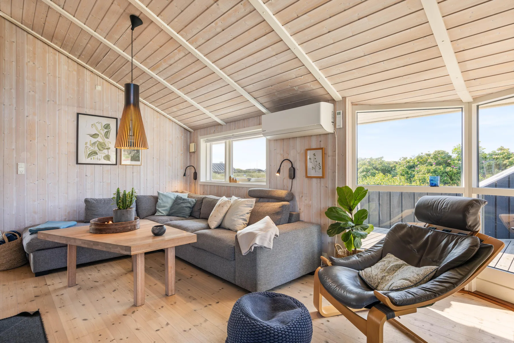 Una sala luminosa con una zona de asientos seccionales y grandes ventanas.