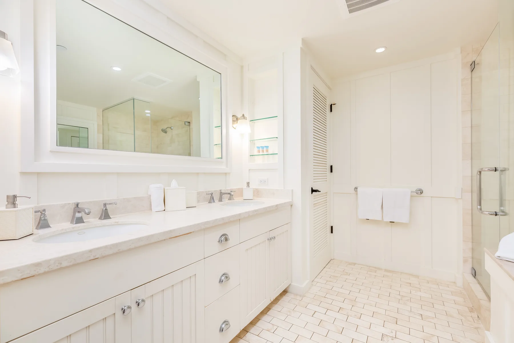 A bright bathroom with a long vanity and a glass shower.