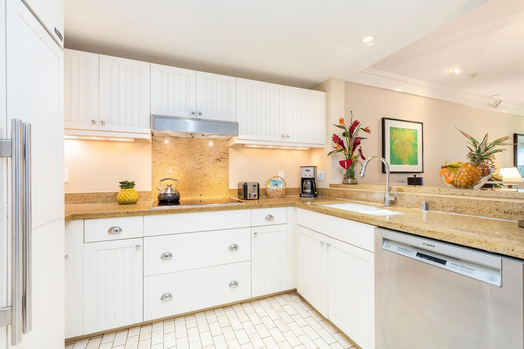 A bright kitchen with white cabinetry, stone countertops, and stainless steel appliances.