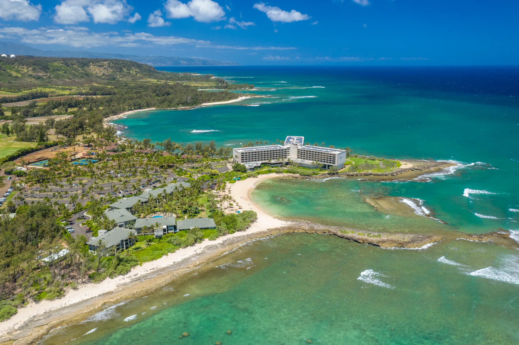 Aerial view of a coastal resort beside a turquoise bay and sandy shoreline.