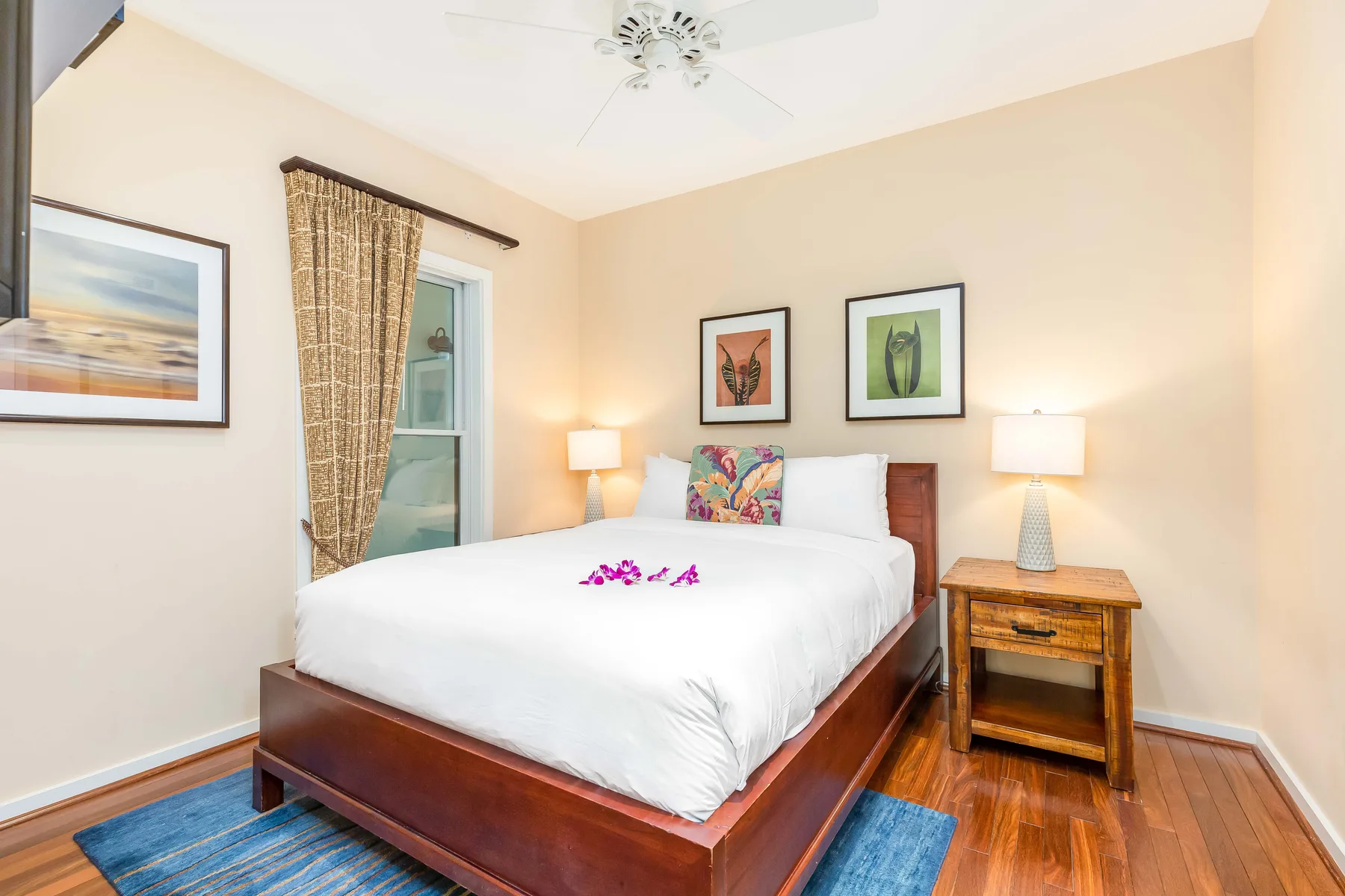A bedroom with a neatly made bed, bedside tables, and framed wall art.