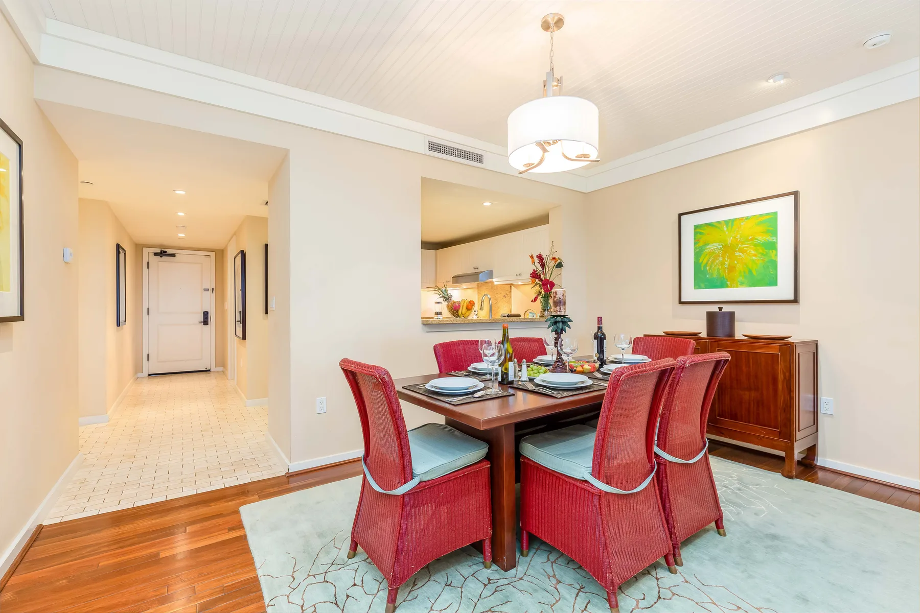 A dining area with a set table and red seating beside a hallway.