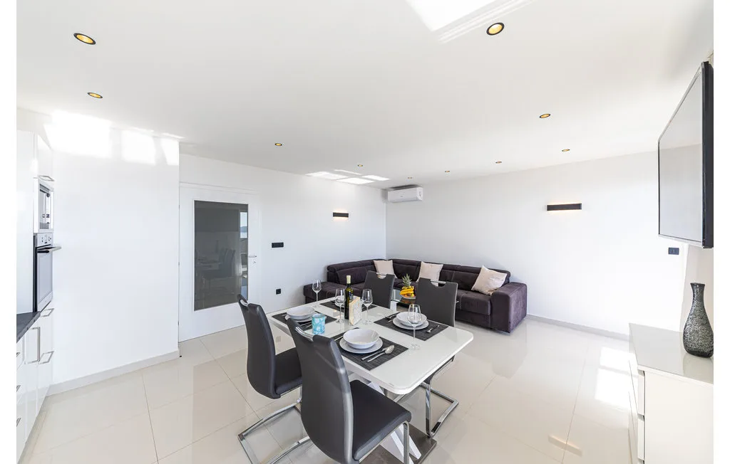A bright living and dining area with a dark sectional and dining table.