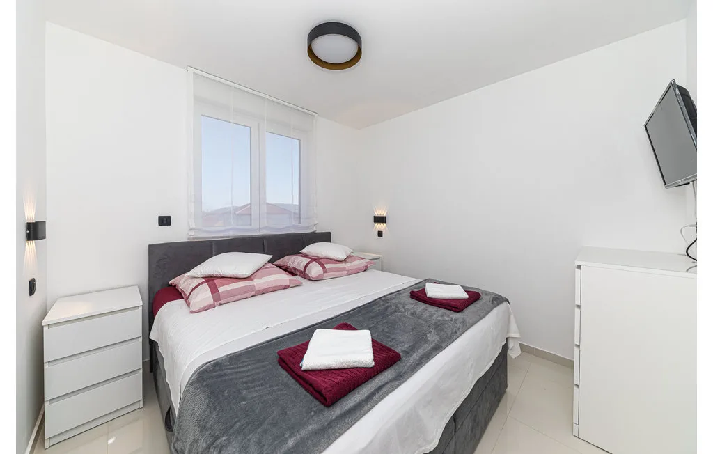 Un dormitorio luminoso con una cama doble y una ventana detrás.