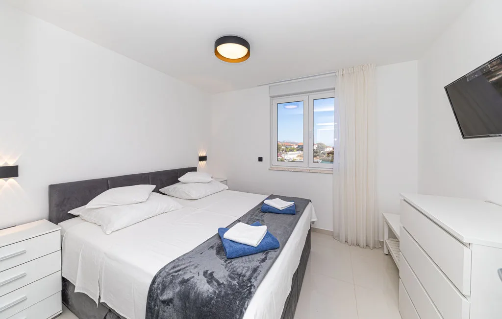 Un dormitorio luminoso con una cama bien hecha y una ventana.